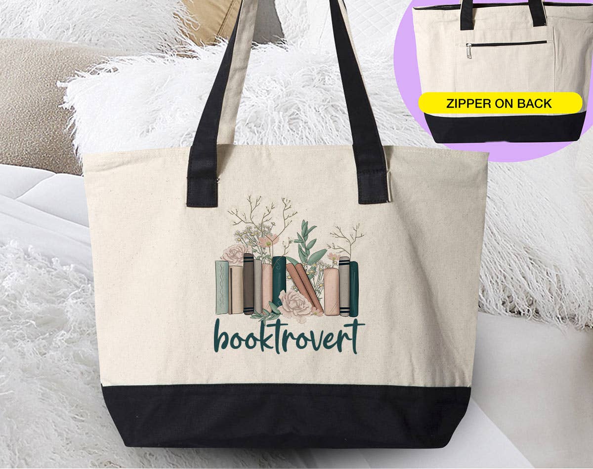 Canvas zipper tote with natural cotton body, black base and handles, and a botanical book graphic above “booktrovert”; Booktrovert - Book Reading Introvert.