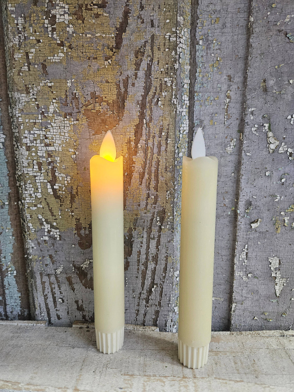 Cream Moving Flame taper candles in ivory wax, two-pack with ribbed white bases and pointed flickering flame tips.