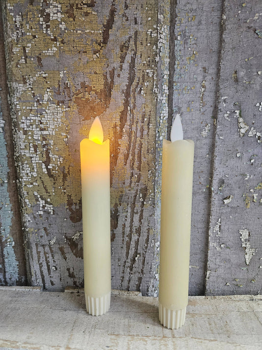 Cream Moving Flame taper candles in ivory wax, two-pack with ribbed white bases and pointed flickering flame tips.