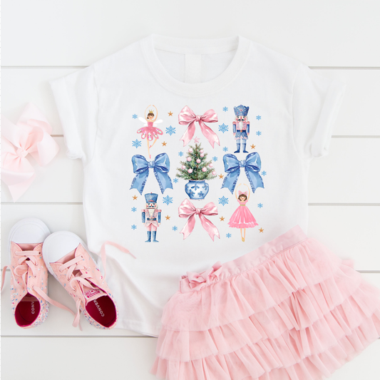White cotton Christmas tee with Coquette Bows, nutcracker soldiers, ballerinas, a decorated tree and pastel blue accents.