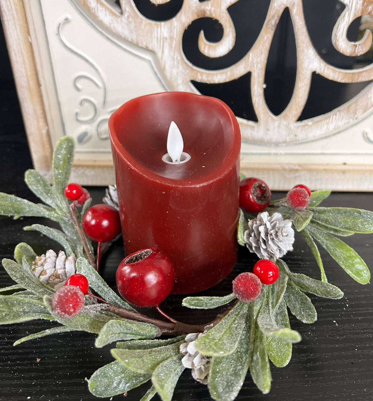 Mistletoe 4.5in Candle Ring with frosted green leaves, red berries, and white pinecones surrounding a red candle.