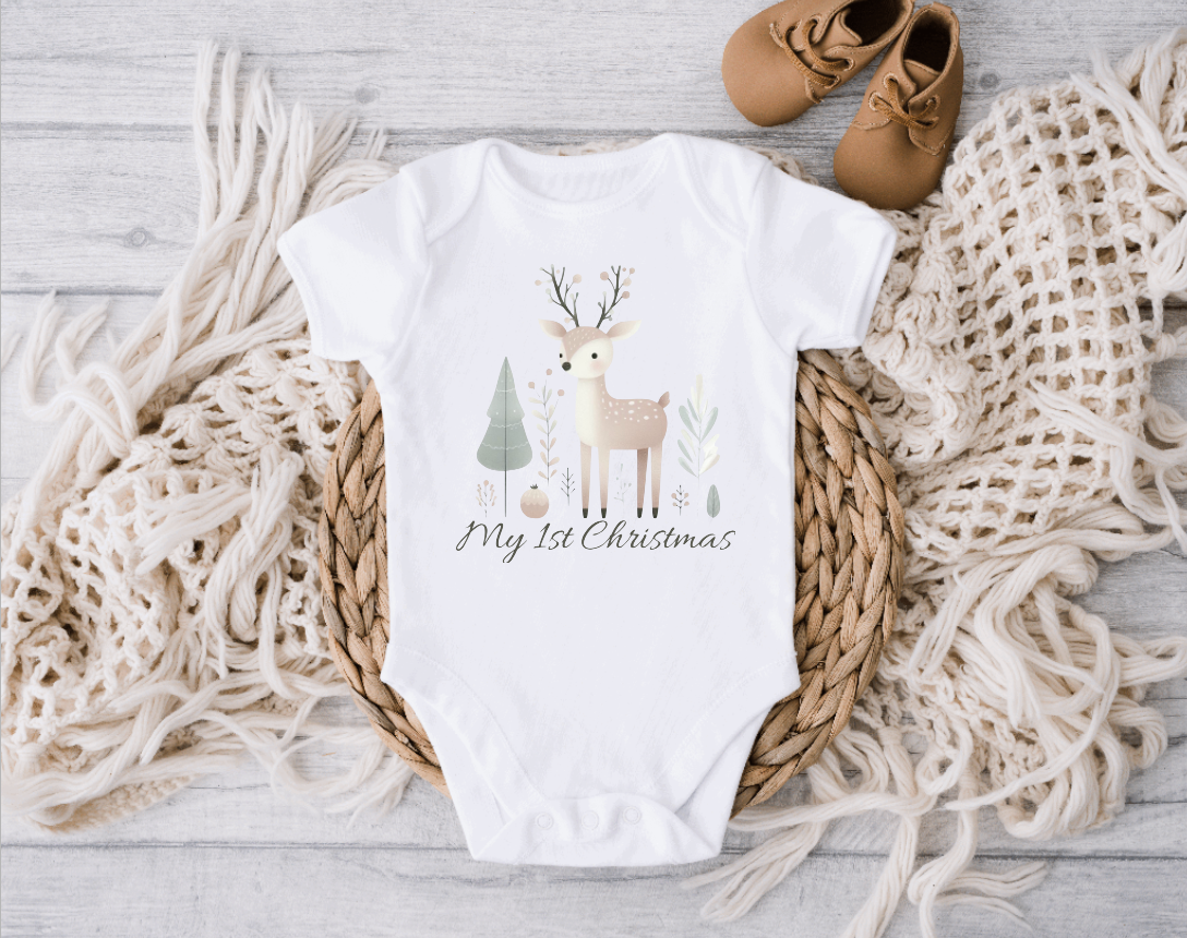 Baby bodysuit in white cotton with a pastel reindeer, trees and “My First Christmas” lettering print.