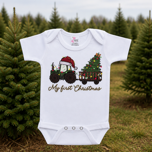 Baby bodysuit in white cotton with a colorful Christmas tractor and tree design, featuring the words My First Christmas.
