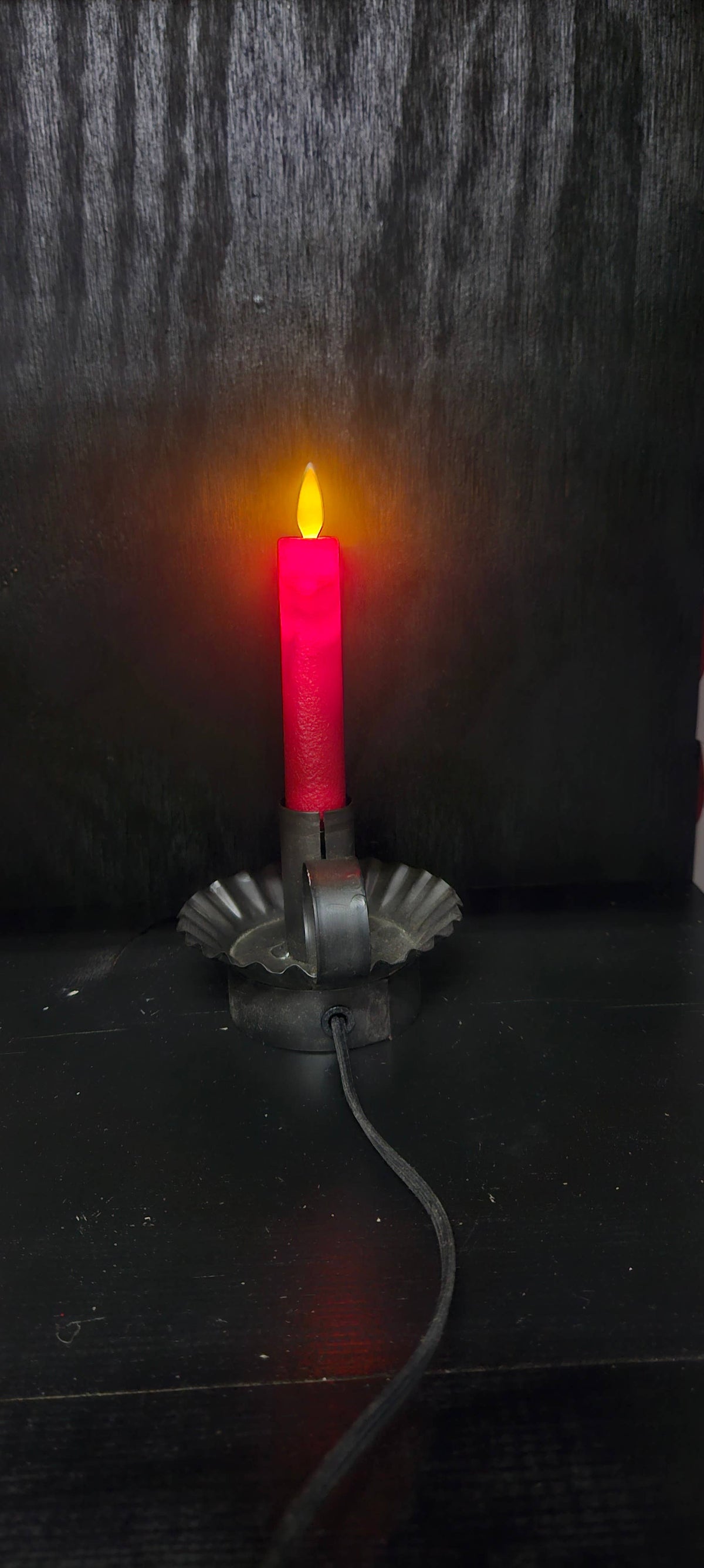 Red Electric Moving Flame LED taper candle in bright red, with a glowing yellow flame and black corded base.